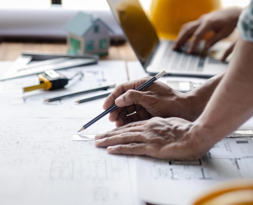 Close-up of a pair of hands drawing out construction plans