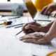 Close-up of a pair of hands drawing out construction plans