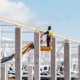 Image of a worker on a lift, welding support beams for a warehouse.